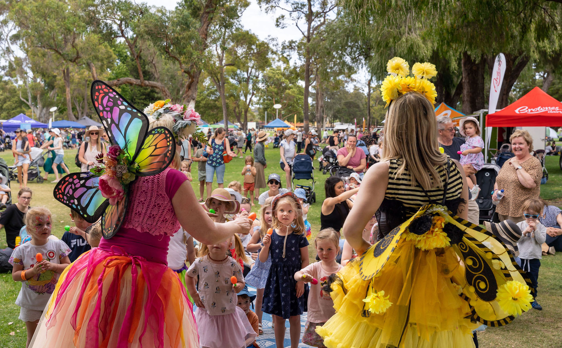 Children watching and part taking in a show presented by colourful fairies. 