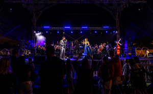 Two singers on stage at a music event at night.